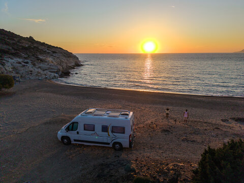 Sunset over Paralia Agios Ioannis in Milos, Greece with a peaceful camper by the shoreline