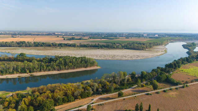 Aerial view of the Po River with low water levels due to drought and summer heatwave, exposing sediments, beaches, and riverbed in Castelvetro Piacentino, Emilia-Romagna, Italy.