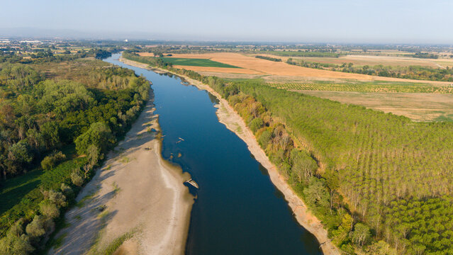 Aerial view of the Po River with low water levels caused by a summer heatwave, exposing wide sediment beaches and the riverbed in Castelvetro Piacentino, Emilia-Romagna, Italy.
