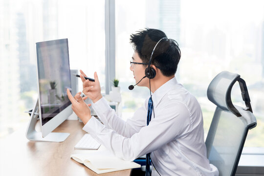 Young businessman with headset working at computer in modern office