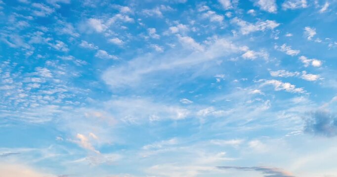 Beautiful time lapse of blue sky with white cumulus and cirrus clouds moving at sunset