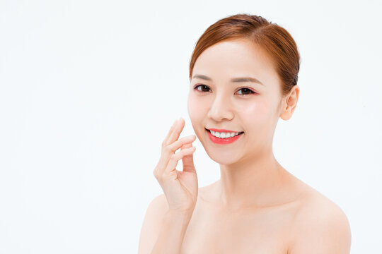 Beautiful young woman with bare shoulders touching her face for skincare