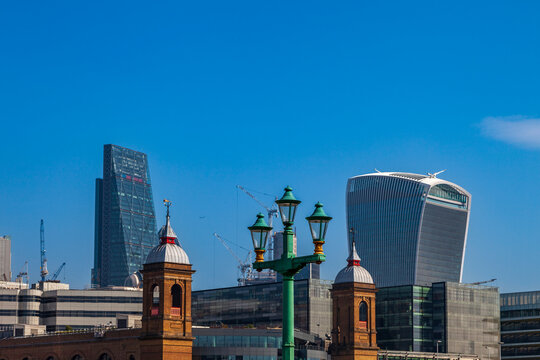 London's modern skyline featuring the walkie-talkie and cheesegrater buildings under a clear blue sky