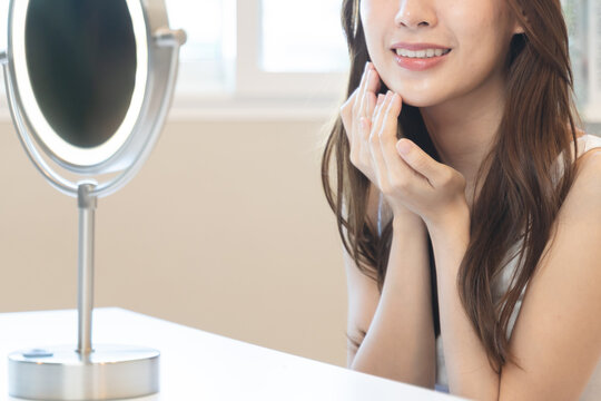 Close up young beautiful asian woman looking at mirror at home