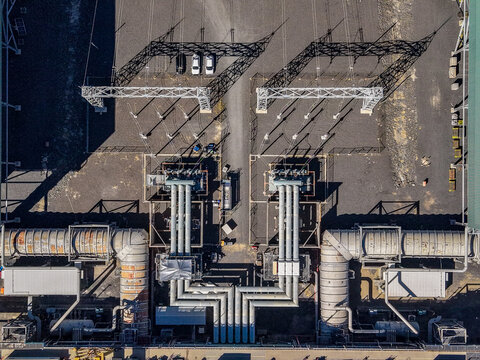 Aerial view of the Millmerran Power Station showing industrial infrastructure with large pipes, electrical transformers, and gravel ground in Domville, Queensland, Australia.
