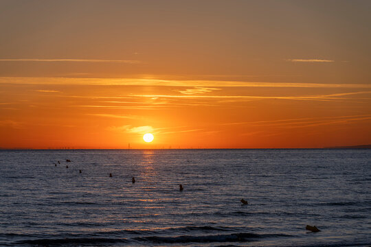 Luc-Sur-Mer, France - 08 08 2022:  Colorful sunrise over the sea and port of Le Havre far away