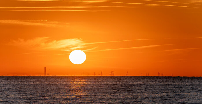 Luc-Sur-Mer, France - 08 08 2022:  Colorful sunrise over the sea and port of Le Havre far away