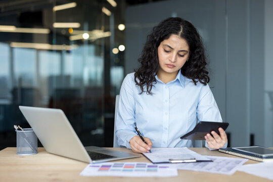 Businesswoman calculating finances and analyzing paperwork in office