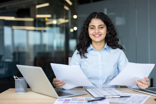 Young businesswoman holding documents smiling at office workplace