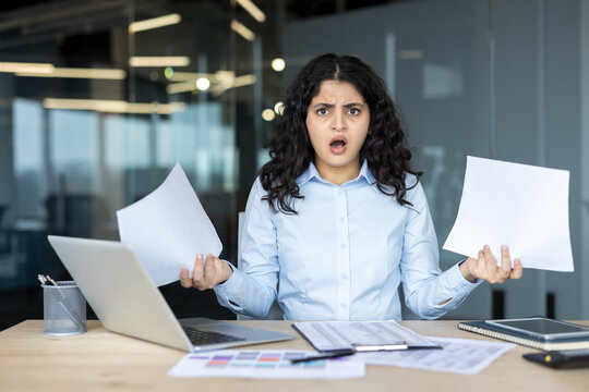 Frustrated businesswoman reacting to shocking paperwork mistake at office