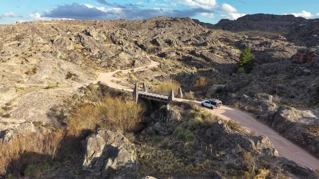 Offroad truck driving over historic suspension bridge along the Old Altas Cumbres road in Cordoba