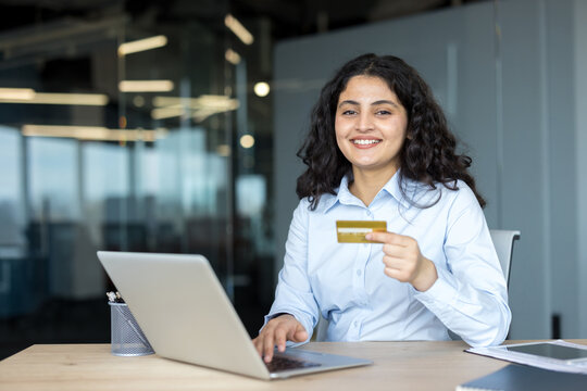 Smiling woman holding credit card using laptop for online shopping