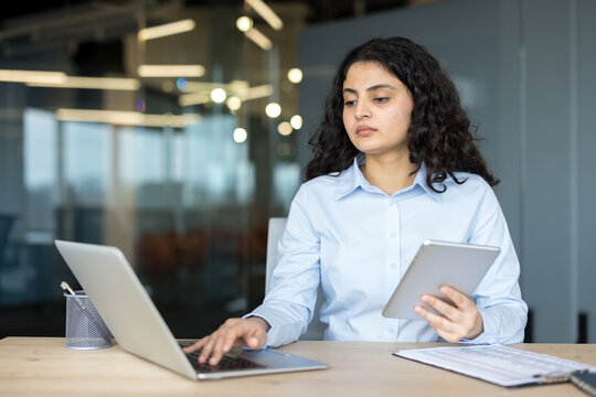 Young businesswoman multitasking using laptop and digital tablet