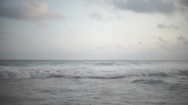 Gentle waves lap against a tranquil shore under a soft overcast sky creating a calming seascape
