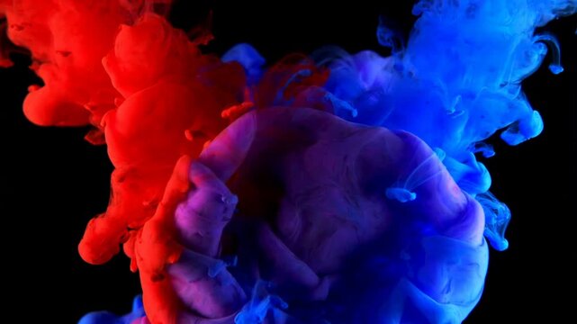 Dramatic red and blue ink clouds colliding and mixing in water with explosive fluid diffusion and bold color contrast in abstract motion