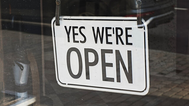 Yes we're open sign displaying business status, inviting people into a store or shop and indicating readiness to serve