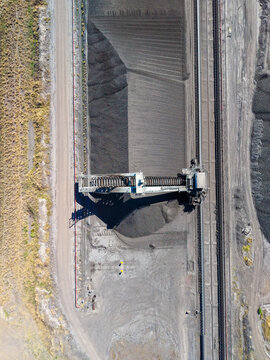 Aerial view of Millmerran Power Station coal handling facility with a stacker reclaimer machine operating over coal stockpiles and railway tracks in Domville, Queensland, Australia.
