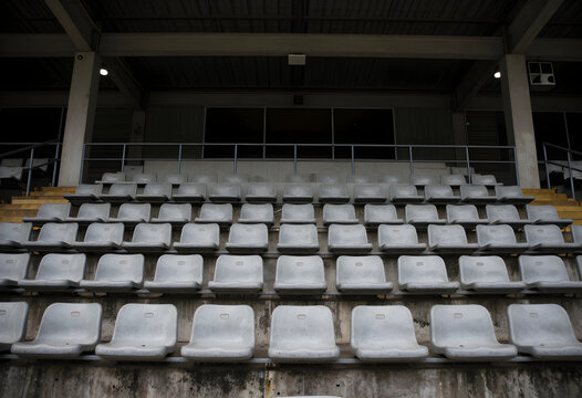 Empty stadium seats, sports event cancellation and social distancing concept, rows of weathered concrete bleachers in an abandoned outdoor arena