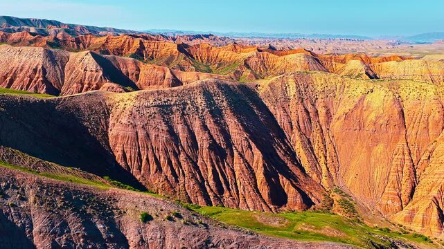 Vibrant red rock landforms stretch across Xinjiang under bright sunlight, capturing the grandeur of colorful mountain ridges.