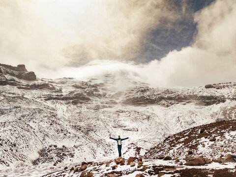 Aerial view of a person standing with arms outstretched on the snow-covered slopes of Volcano Chimborazo in Guano, Chimborazo, Ecuador.
