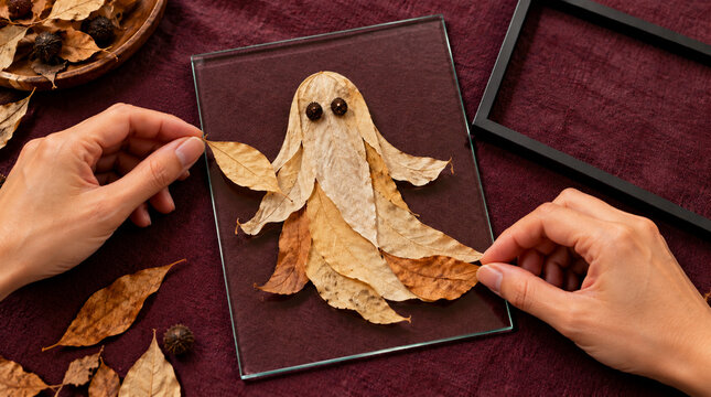 Manos colocando hojas secas en composici&oacute;n de Halloween