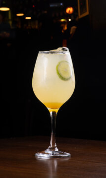 Glass of gin limoncello spritz isolated on a wooden table, angled view, blurred background.