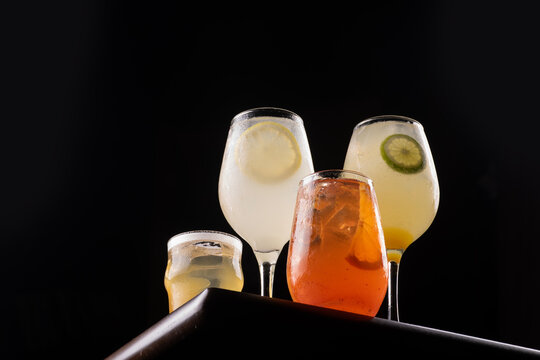 Collection of refreshing, colorful cocktails on a black background, low-angle shot.