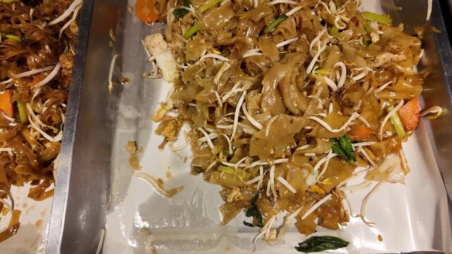 Close up shot of traditional Thai stir fried wide rice noodles with soy sauce, bean sprouts and vegetables at a street food market.