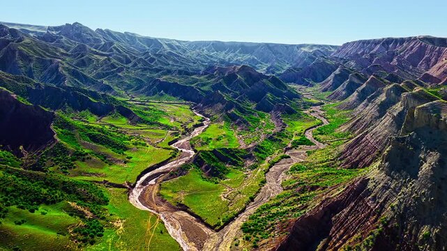High angle view of dramatic landforms and colorful rock layers in Xinjiang Danxia landform canyon during sunny day.