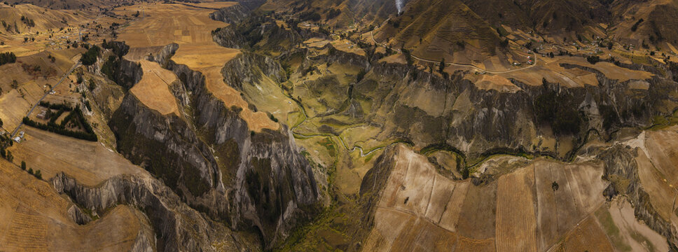 Aerial view of Toachi River Canyon with deep rocky gorges, winding river, and golden agricultural fields in Zumbahua, Cotopaxi, Ecuador.