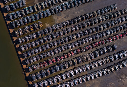 Aerial view of rows of scrapped heavy-duty truck engines arranged in a salvage yard near a riverbank in Kalamazoo, Michigan, United States.