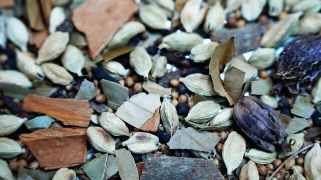Close-up of assorted dried spices and botanicals, Close-up view of assorted dried spices, cardamom pods, cinnamon bark, seeds, leaves, and botanical pieces arranged in a natural textured mix.