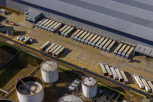 Aerial view of Hemel Hempstead Industrial Estate with rows of parked semi-trucks, large industrial storage tanks, and warehouse facilities in London, England, United Kingdom.