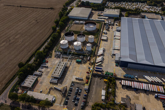 Aerial view of Hemel Hempstead Industrial Estate featuring large storage tanks, a warehouse facility, and numerous trucks parked in the loading area, London, England, United Kingdom.