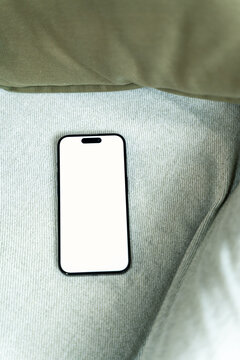 Smartphone with blank white screen on green fabric surface
