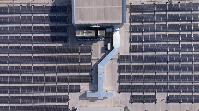 Top down ascending aerial view of the rooftop solar panel array on an EV charging station in the UK