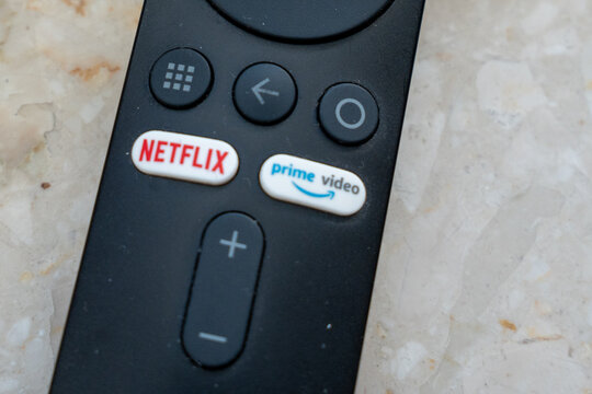 Warsaw, Poland - Sep 30, 2026: Close-up of Netflix and Prime Video buttons on a black remote control, streaming service shortcut keys with home, back and volume controls above a marble surface