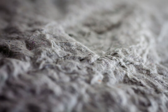 Extreme close up of old gray handmade paper clay with a structure and rough texture. Paper recycling. Selective soft focus, shallow depth of field.