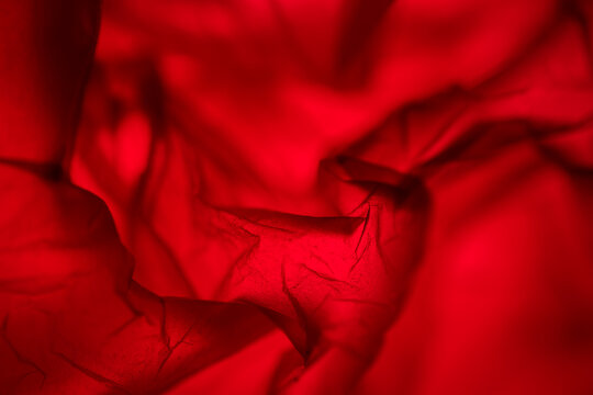Extreme close up of red plastic texture background. The plastic surface is wrinkly and tattered making abstract pattern. Selective focus, shallow depth of field.