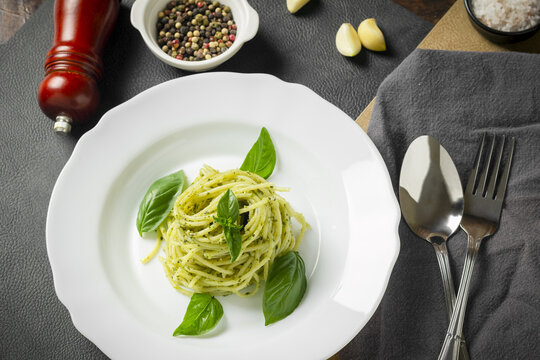Pasta spaghetti with pesto, basil, garlic and spices on dark table. Italy food.