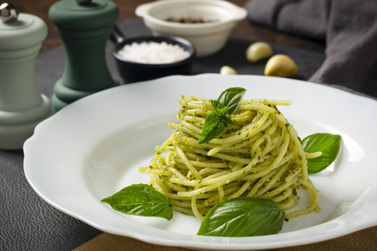 Pasta spaghetti with pesto, basil, garlic and spices on dark table. Italy food.
