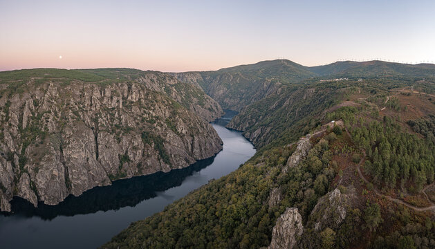 Aerial view of Ribeira Sacra canyon with the Sil River flowing through steep rocky cliffs and lush forests at sunset in Lugo, Ourense, Spain.