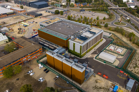 Aerial view of Ark Data Centres Longcross Park, featuring modern industrial buildings, cooling units, and surrounding infrastructure in Chertsey, England, United Kingdom.