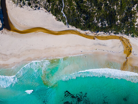 Topdown view of a turquoise water and a creek leading to the ocean