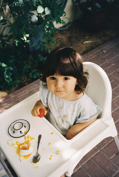 A little girl eating an egg that got smashed on the table