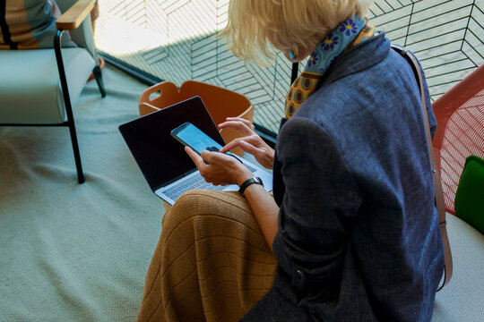 Woman Using Laptop and Smartphone in Modern Indoor Space