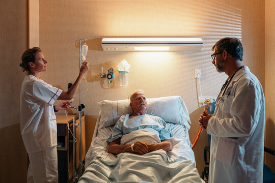 Medical professionals caring for elderly patient in hospital room
