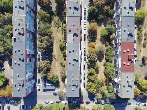 Aerial view of three parallel residential apartment blocks surrounded by lush green trees and parked cars in a suburban neighborhood in Sofia, Sofia City Province, Bulgaria.