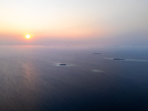 Aerial view of small tropical islands surrounded by calm ocean waters during a golden sunset in Karimunjawa, Central Java, Indonesia.