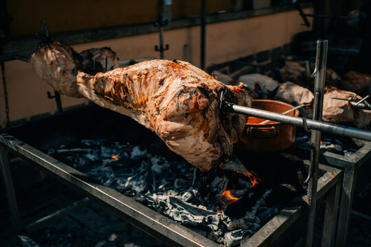 Cooking Meat on a Spit Over Hot Coals in a Market Setting